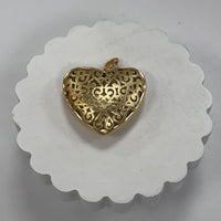Gold heart-shaped pendant on a white scalloped coaster