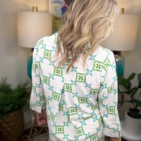 Woman wearing a white blouse with green and blue geometric pattern