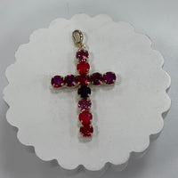 Cross-shaped pendant with red and purple gemstones on a white background