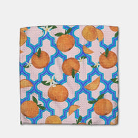 Close up of a dishcloth with a pattern of oranges on a geometric blue and light pink background