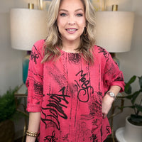 Woman wearing a pink top with black text in an indoor setting