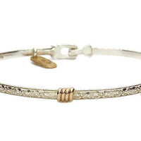 Silver band bracelet with gold wrap detail.