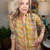 Woman wearing a colorful patterned dress in an indoor setting with decor elements.