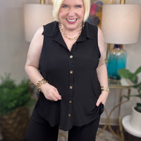 Woman wearing a black sleeveless top and pants with gold buttons.