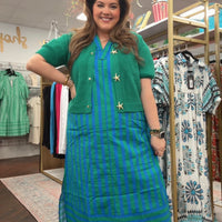 Woman wearing a green dress with a striped skirt in a clothing store.