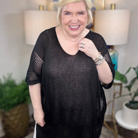 Woman wearing a black short-sleeved tunic sweater.