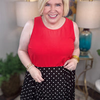 Woman wearing a red top and black polka dot skirt