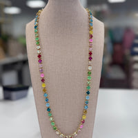 Multicolored gemstone necklace on a mannequin bust with a blurred indoor background