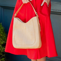 Person wearing a red dress holding a beige handbag