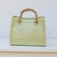 Green handbag with bamboo handle on a light background