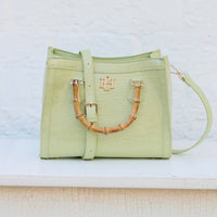 Light green handbag with bamboo handle on a white surface