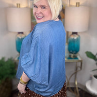 Woman wearing a denim v-neck dolman sleeve blouse