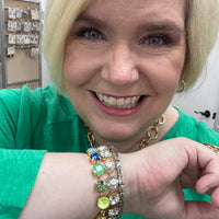 Woman wearing multiple bracelets with colorful gemstones, smiling.