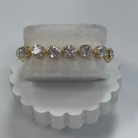 Gold and diamond bracelet on a white stand with a gray background