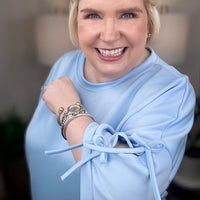Woman wearing a baby blue matching set with bows tied on the sleeves.