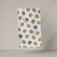 Tea towel with green olive pattern and text on a light pink towel