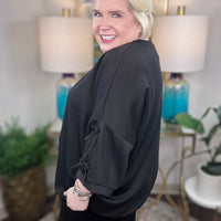 Woman wearing a black matching set with bows tied on the sleeves.