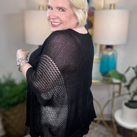 Woman wearing a black short-sleeved tunic sweater.