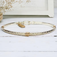 Silver band bracelet with gold wrap detail.