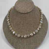 Necklace with clear stones on a brown textured stand against a white background