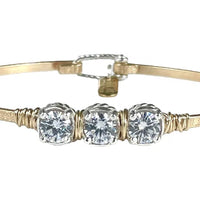 Gold bracelet with three clear gemstones on a white background
