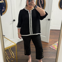 Person wearing a black outfit with white trim in front of a mirror.