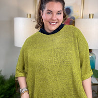 Woman wearing a short sleeved chartreuse sweater.