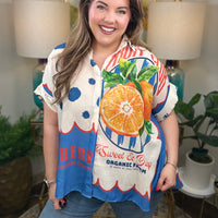 Woman wearing a bright colorful linen blend with a fruit pattern button down top.