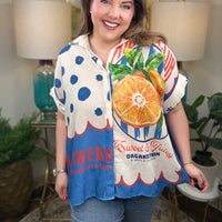 Woman wearing a bright colorful linen blend with a fruit pattern button down top.