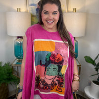 woman wearing a sleeveless bright pink top with a large colorful Frida Kahlo graphic print on the front