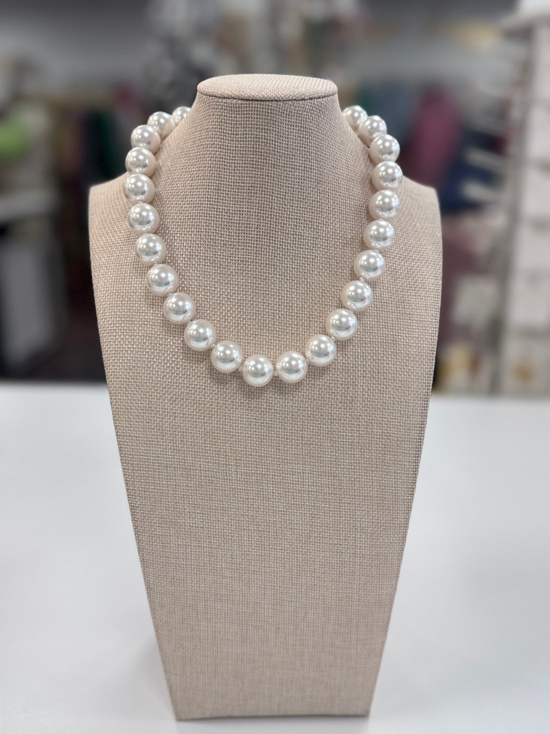 Pearl necklace on a beige display bust with a blurred background