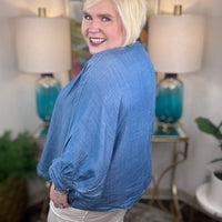 Woman wearing a denim v-neck dolman sleeve blouse