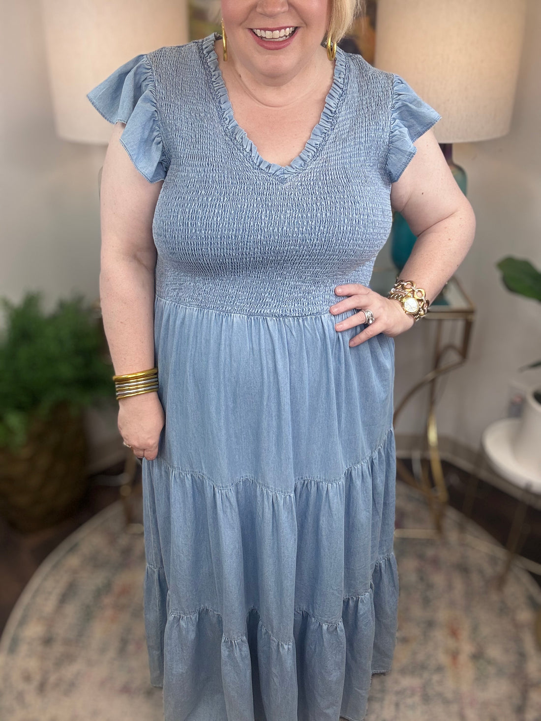 A woman wearing a light blue denim maxi dress with a smocked bodice and short ruffled sleeves