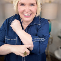 Woman wearing a navy shirt dress in a home setting with lamps and decor.
