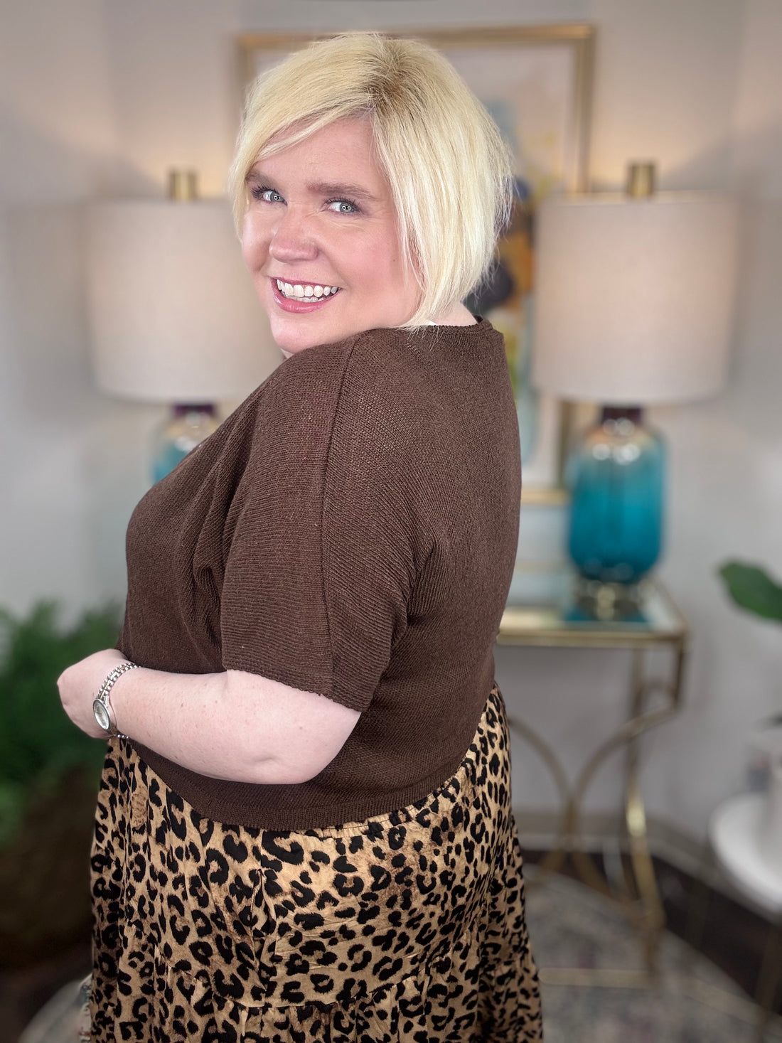 Woman wearing a brown cardigan and leopard print skirt indoors.