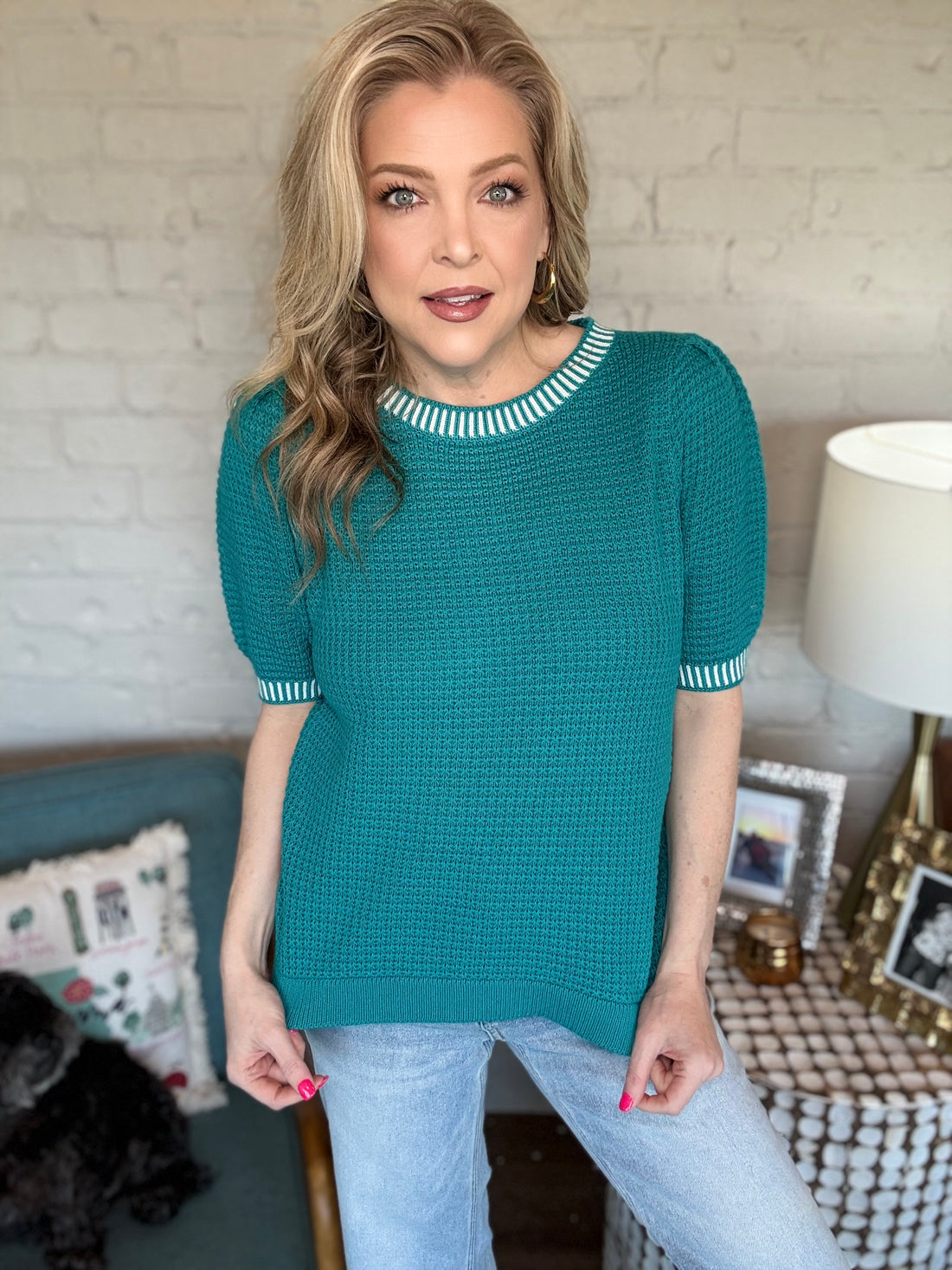 Woman wearing a teal sweater with white trim.