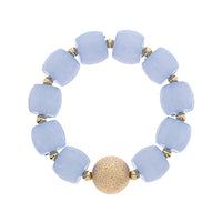 Bracelet with light blue beads and a gold bead on a white background