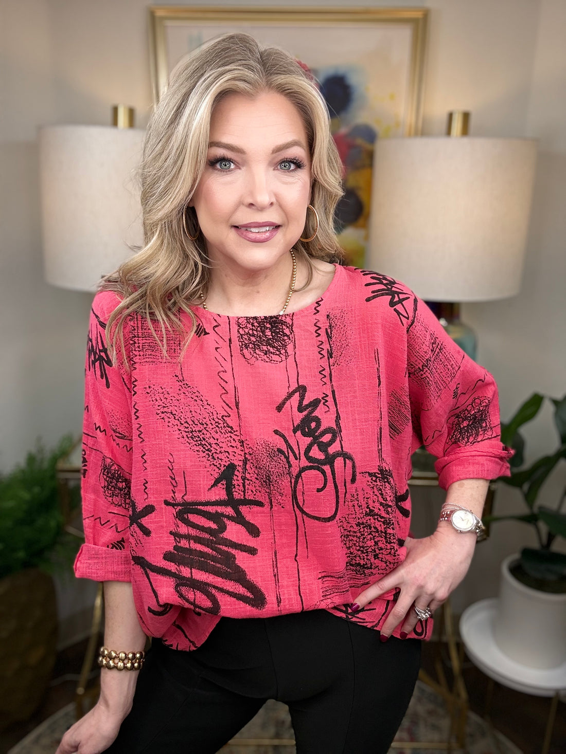 Woman wearing a pink top with black text in an indoor setting