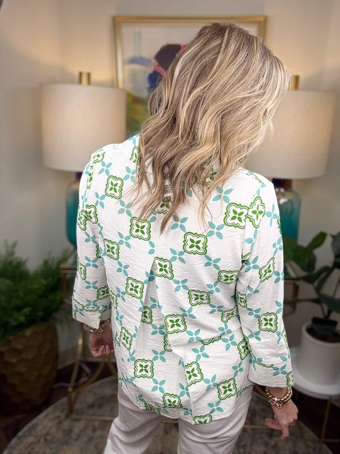 Woman wearing a white blouse with green and blue geometric pattern