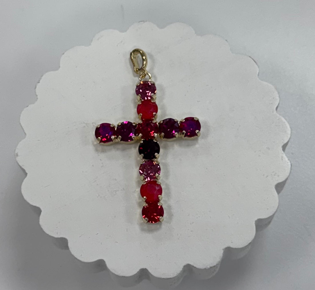 Cross-shaped pendant with red and purple gemstones on a white background