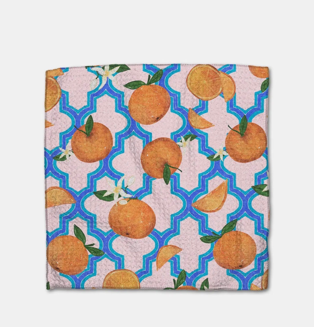 Close up of a dishcloth with a pattern of oranges on a geometric blue and light pink background
