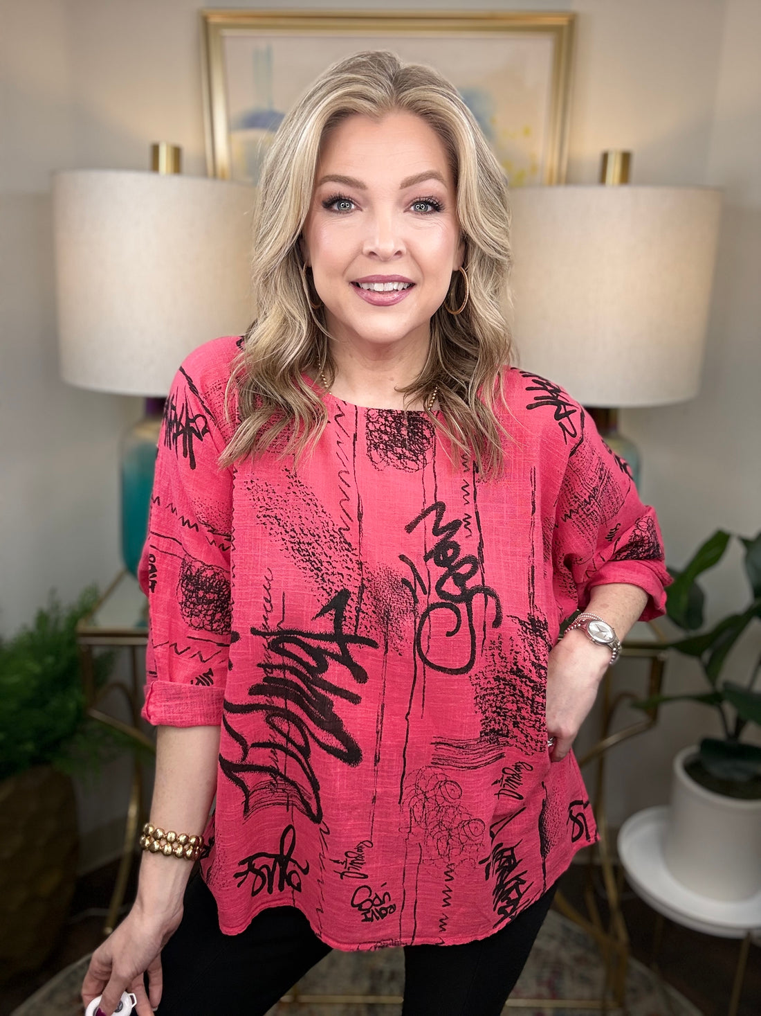 Woman wearing a pink top with black text in an indoor setting