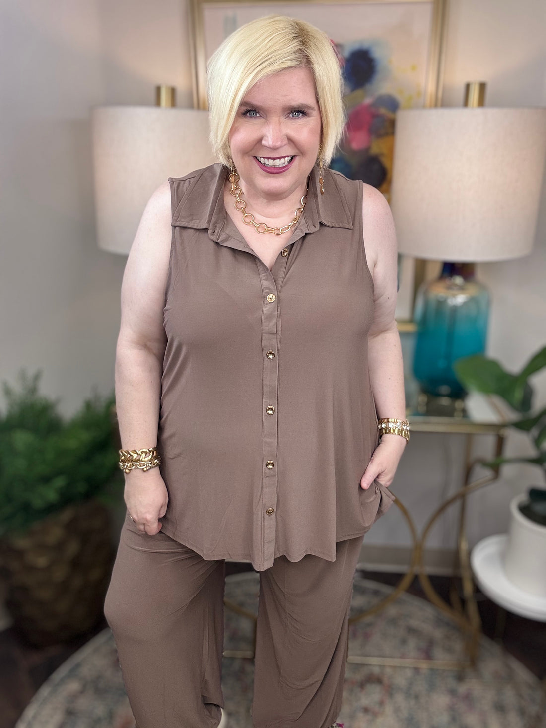 Woman wearing a mocha brown sleeveless top and pants with gold buttons
