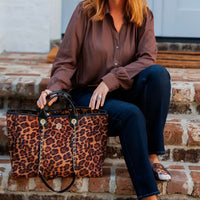 Person holding a leopard print handbag on a brick step