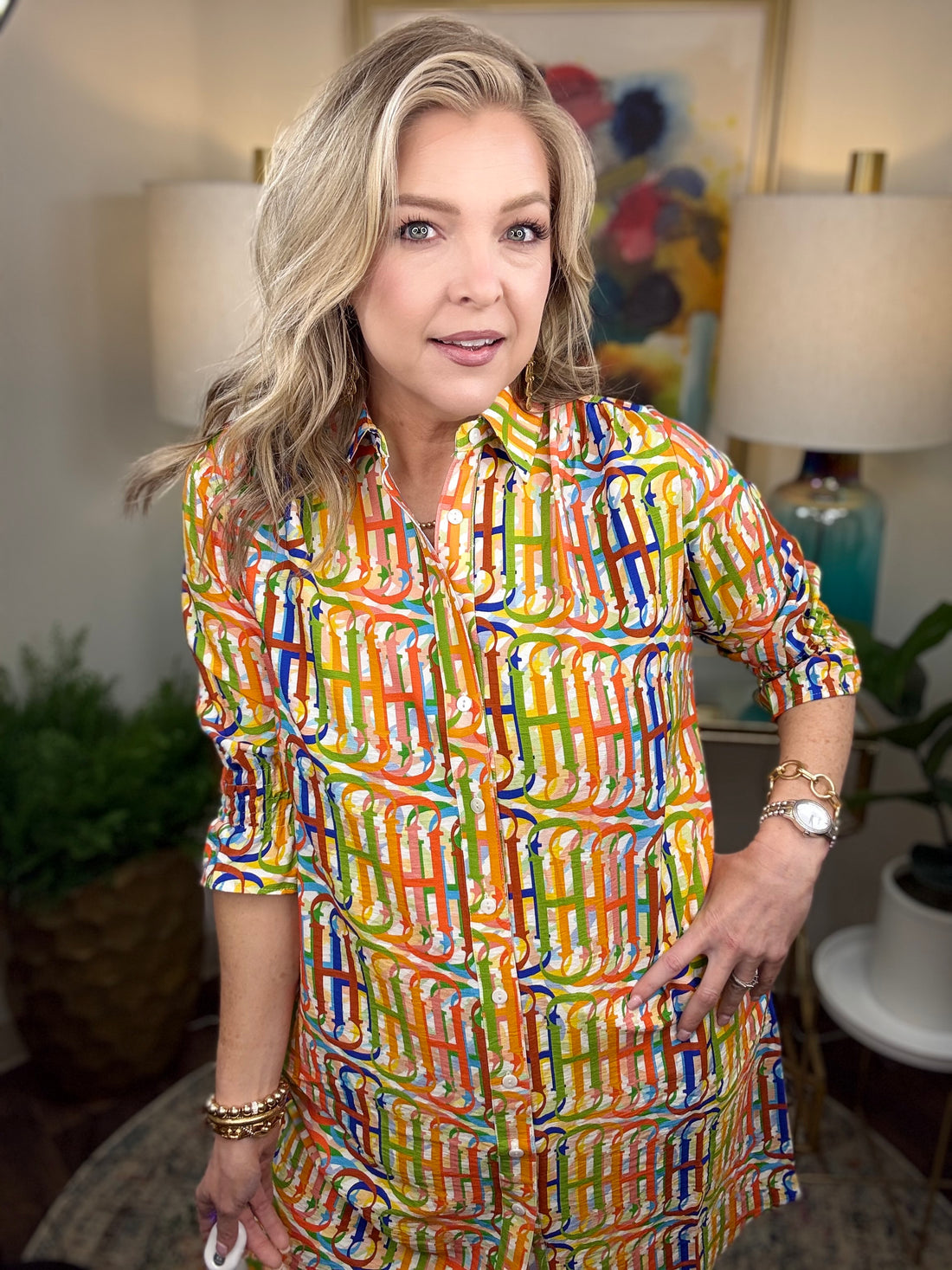 Woman wearing a colorful patterned dress in an indoor setting with decor elements.