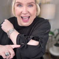 Woman wearing a black matching set with bows tied on the sleeves.