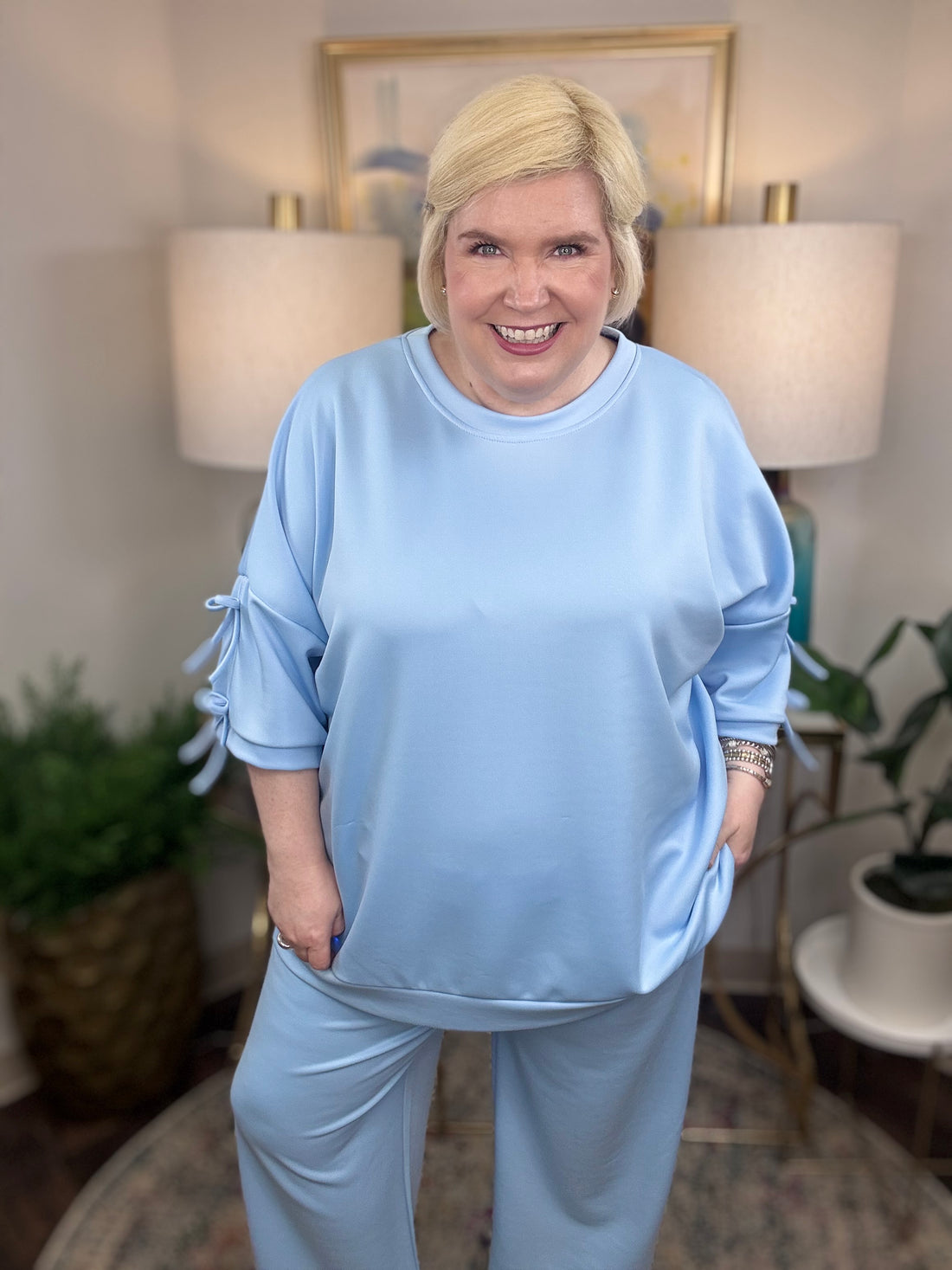 Woman wearing a baby blue matching set with bows tied on the sleeves.