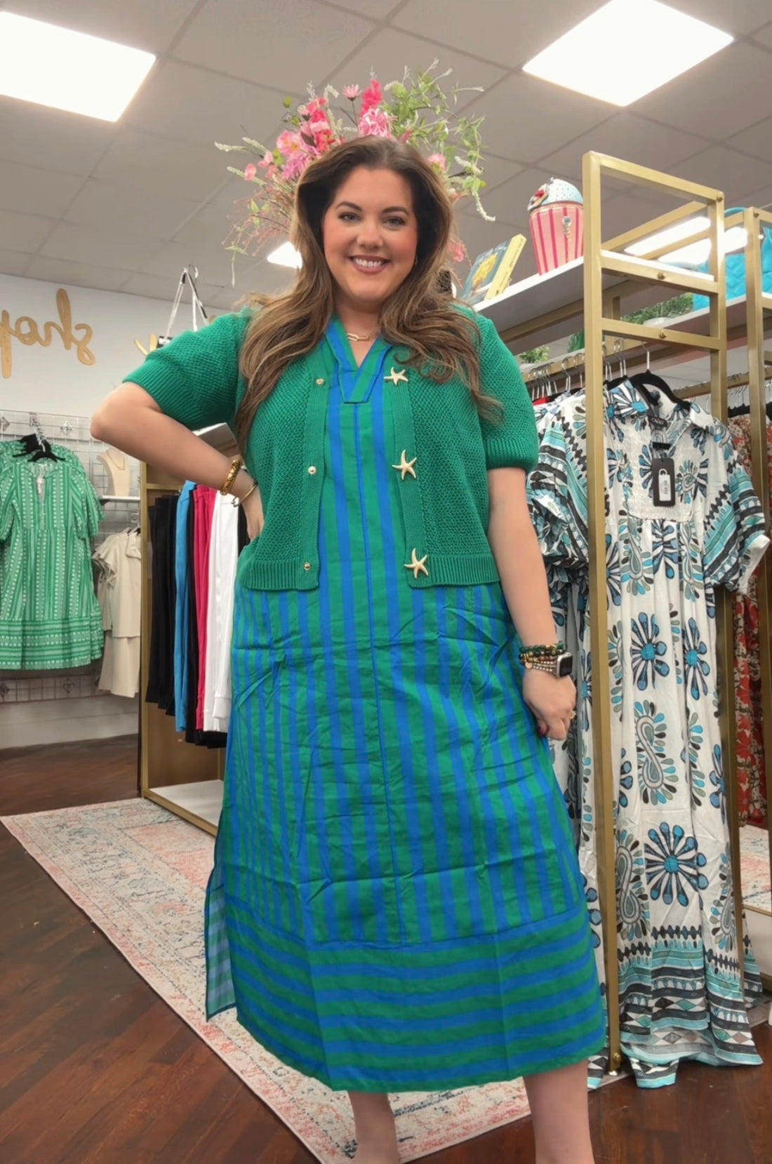 Woman wearing a green dress with a striped skirt in a clothing store.