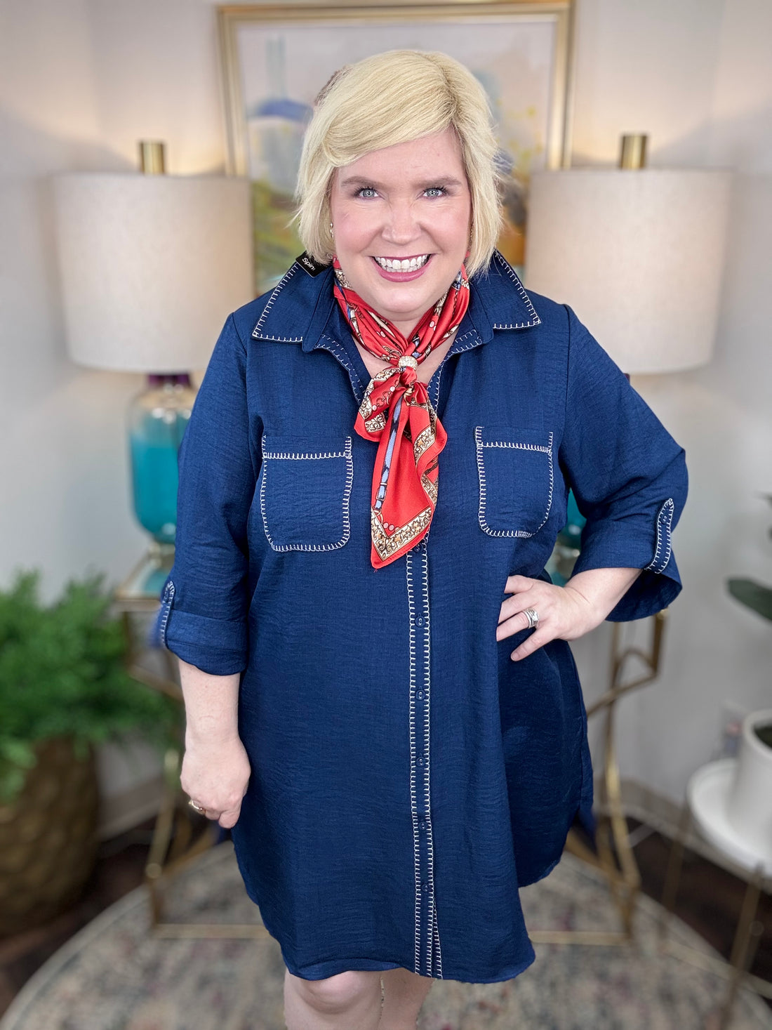 Woman wearing a blue dress with a red scarf in a home setting