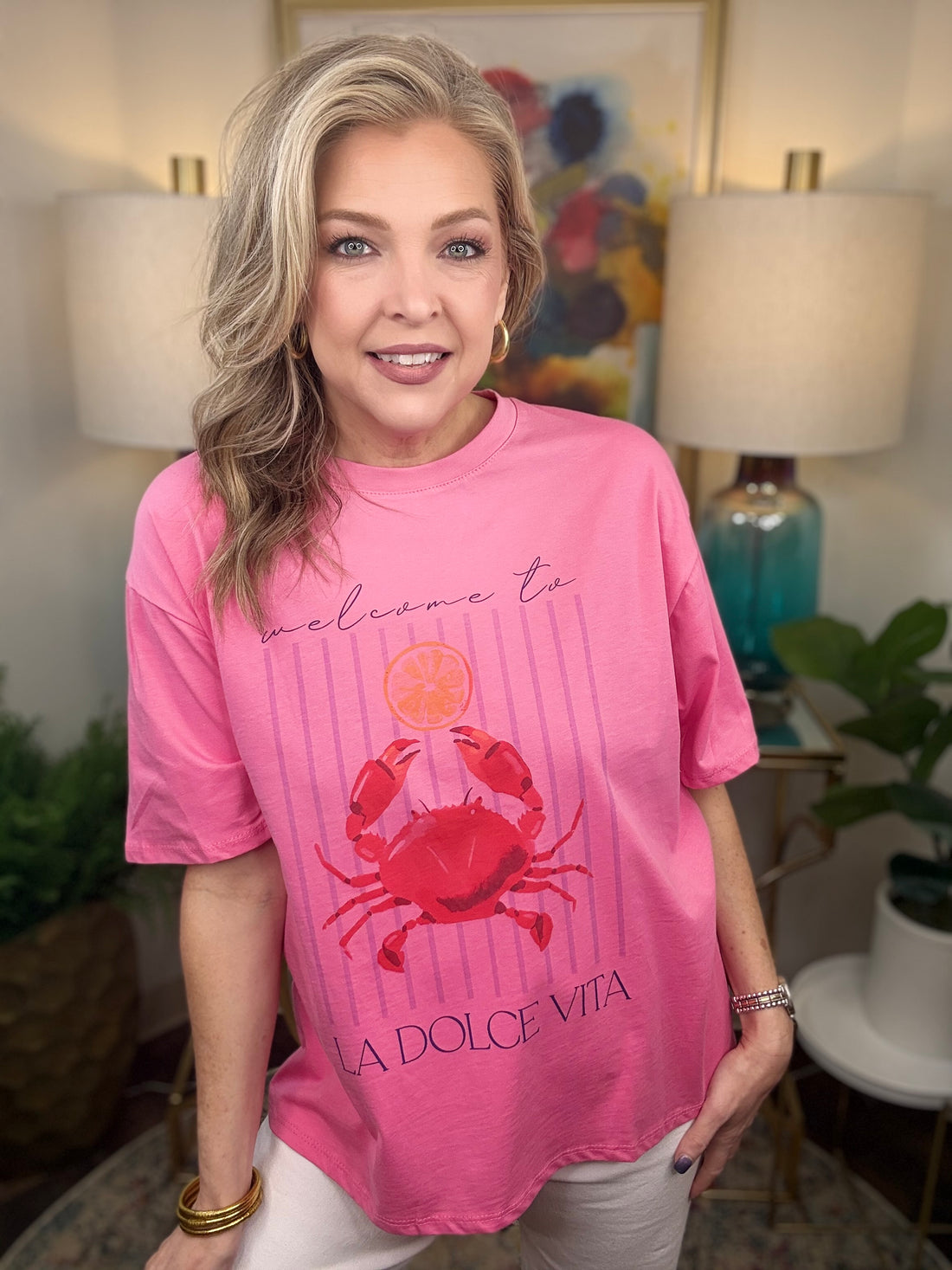 Woman wearing a pink t-shirt with a crab design in a home setting